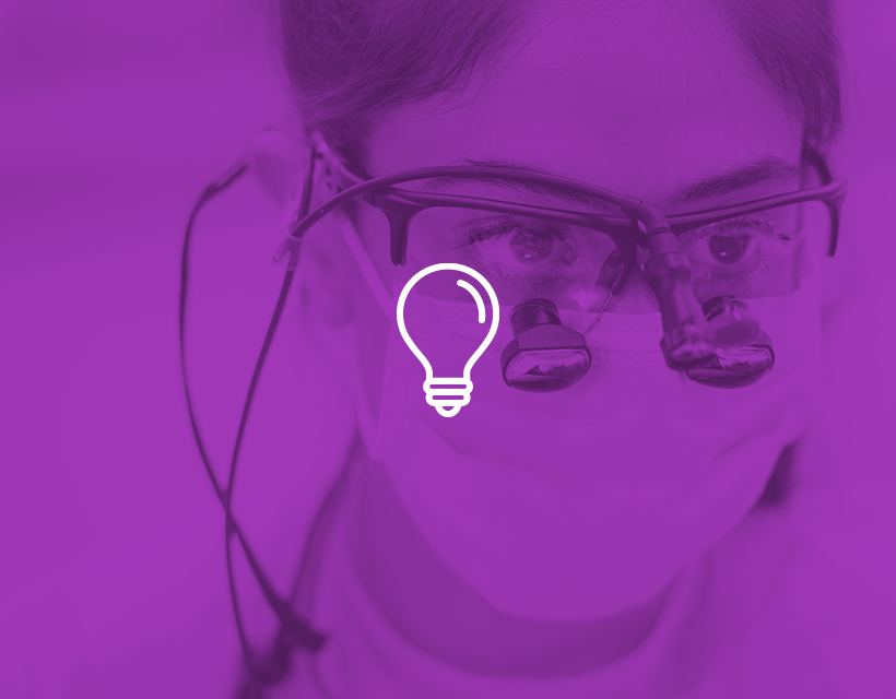Lightbulb icon with purple filter overlaid on an image of a dental provider looking through goggles
