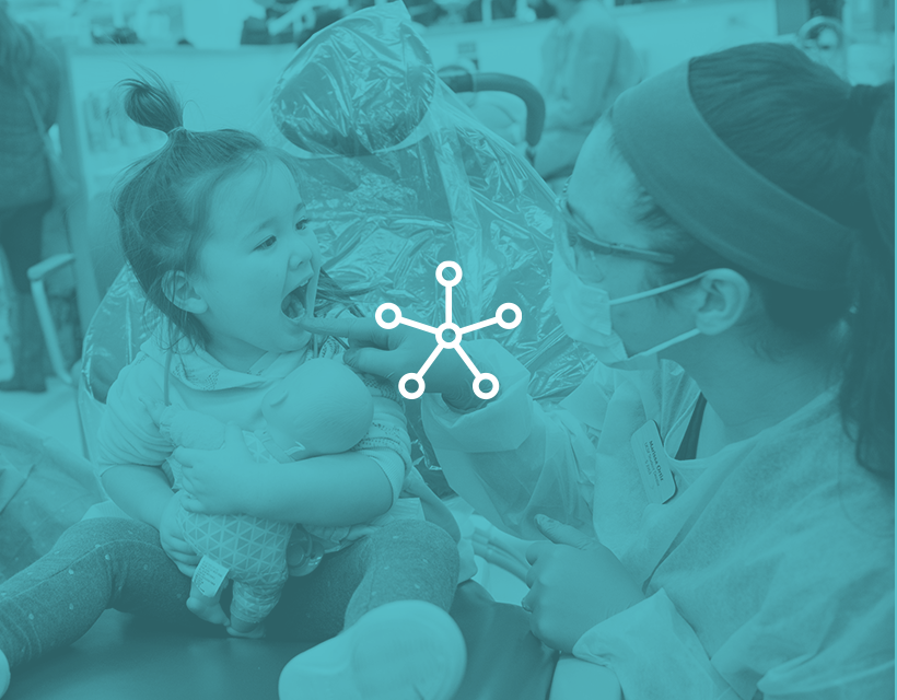 Spokes icon with a blue filter over an image of providers working with a toddler-aged patient