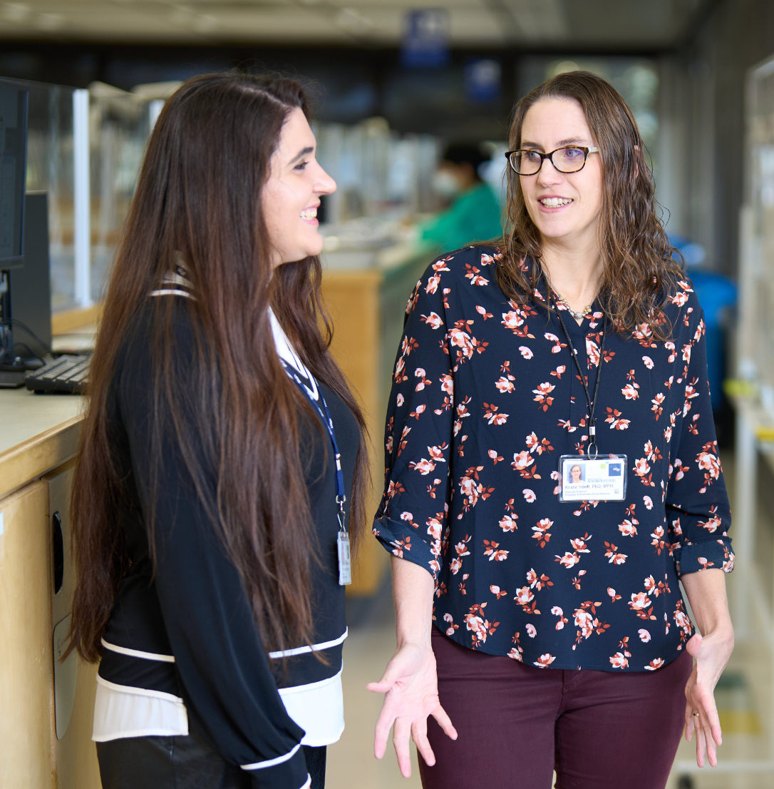 A dental professional wearing magnifying loupes and a face mask performs a procedure on a patient.