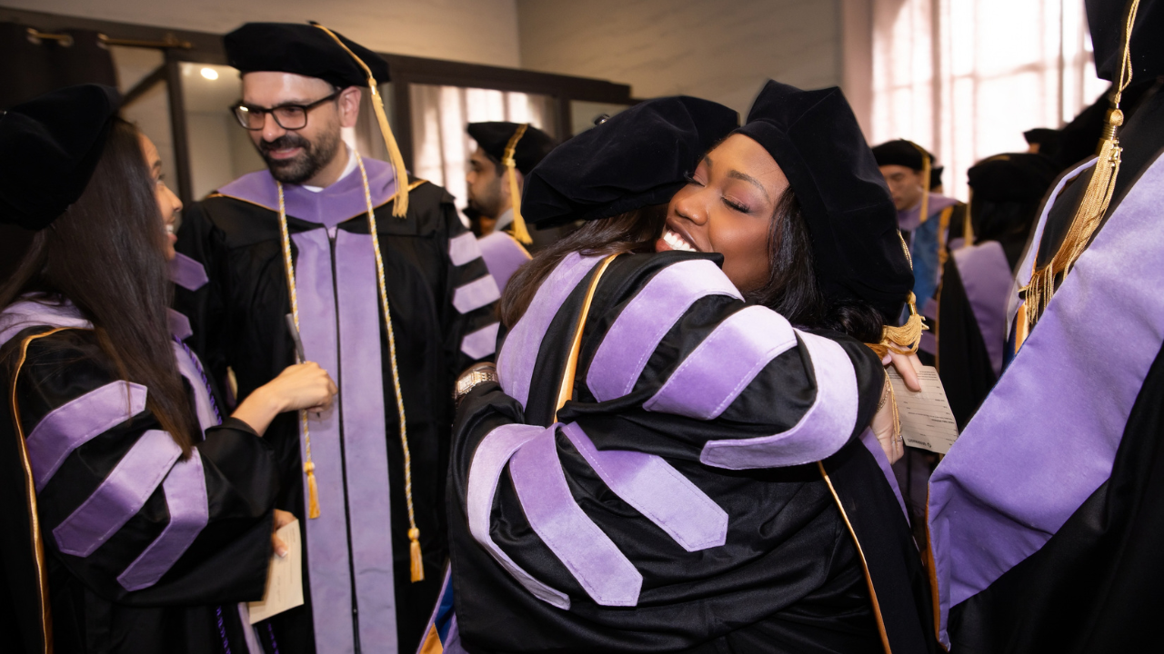 2025 School of Dentistry graduates hug before the ceremony