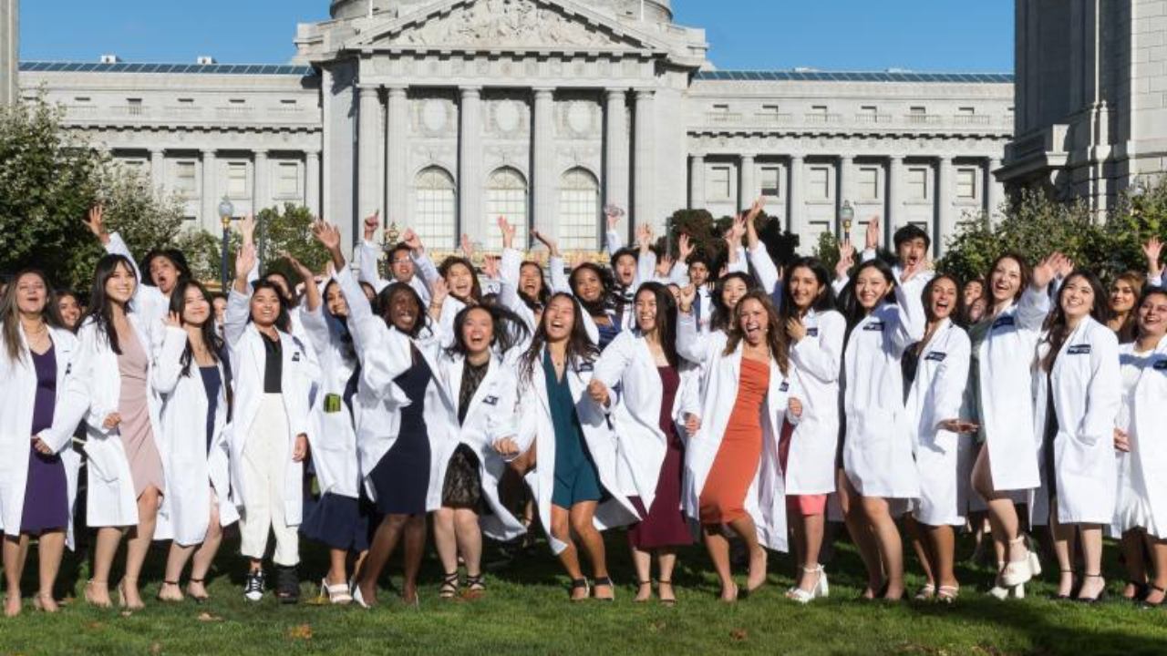 Students pose in their white coats at the annual ceremony.