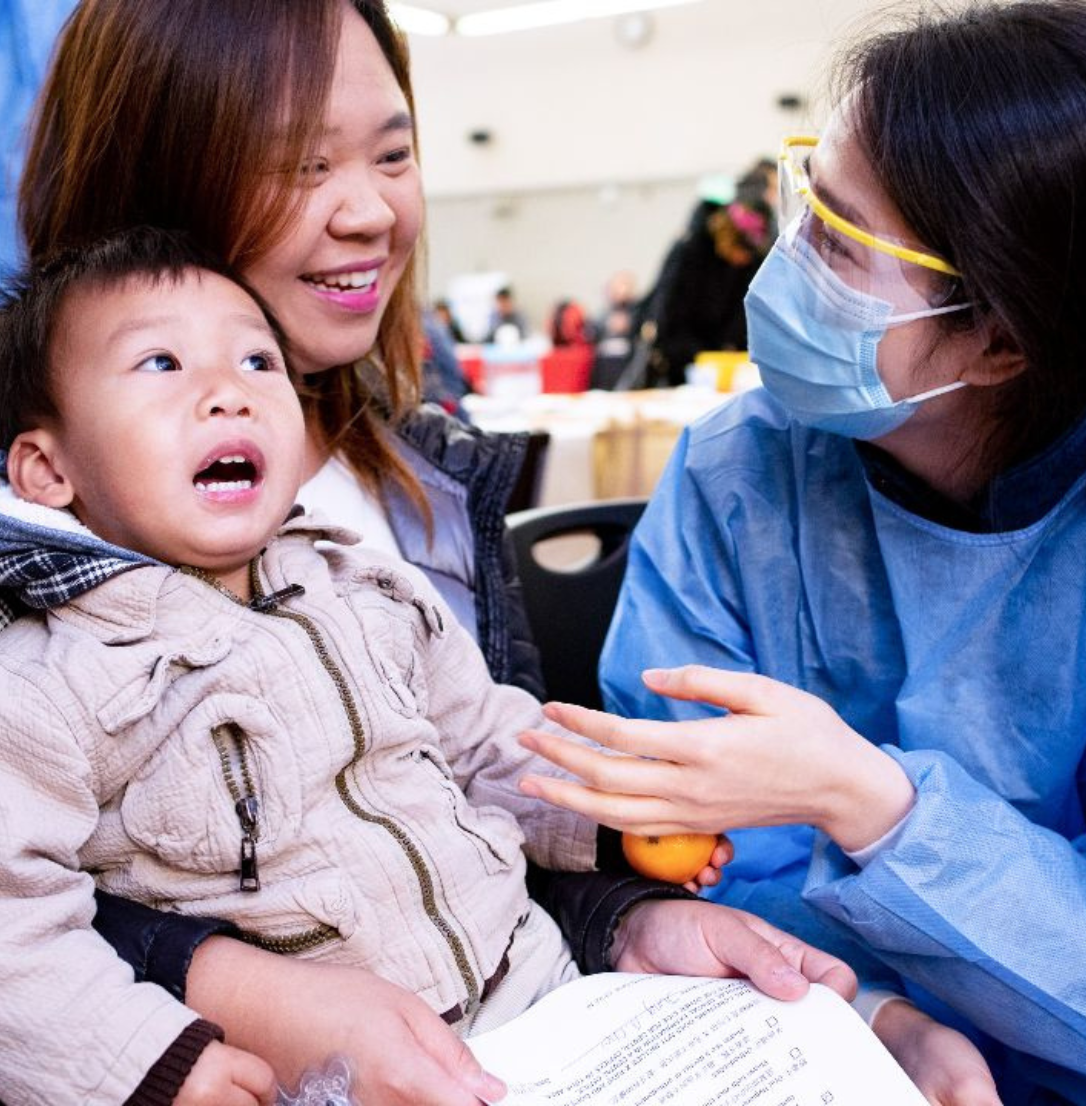 A dental public health provider talks with a mother and child at a community event.