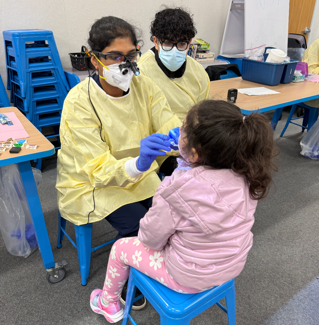 Two dental public health providers providing care to a child patient