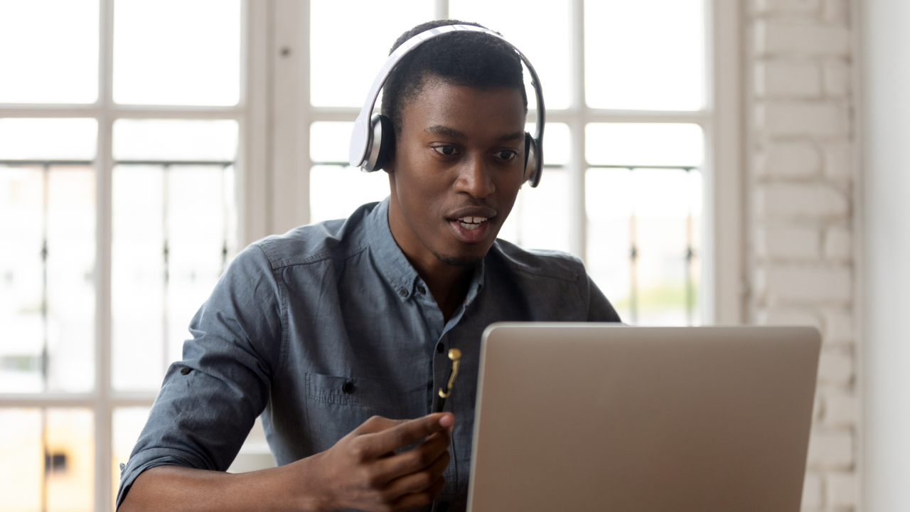 Man wearing headphones on a video call looks at a laptop