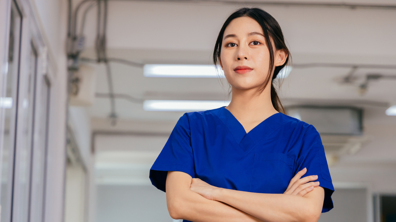 female in scrubs looks at the camera with arms crossed