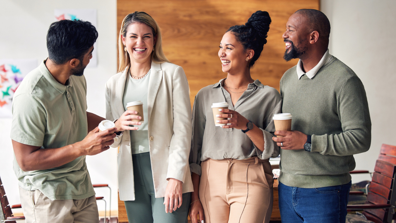 four coworkers drink coffee and chat in the office