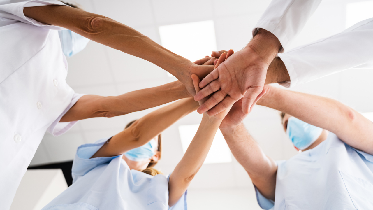 healthcare staff put hands together in a team huddle
