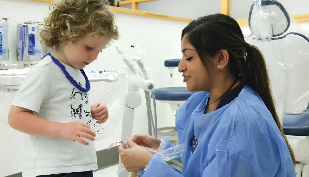 CDC volunteer provider kneels down next to a pediatric patient