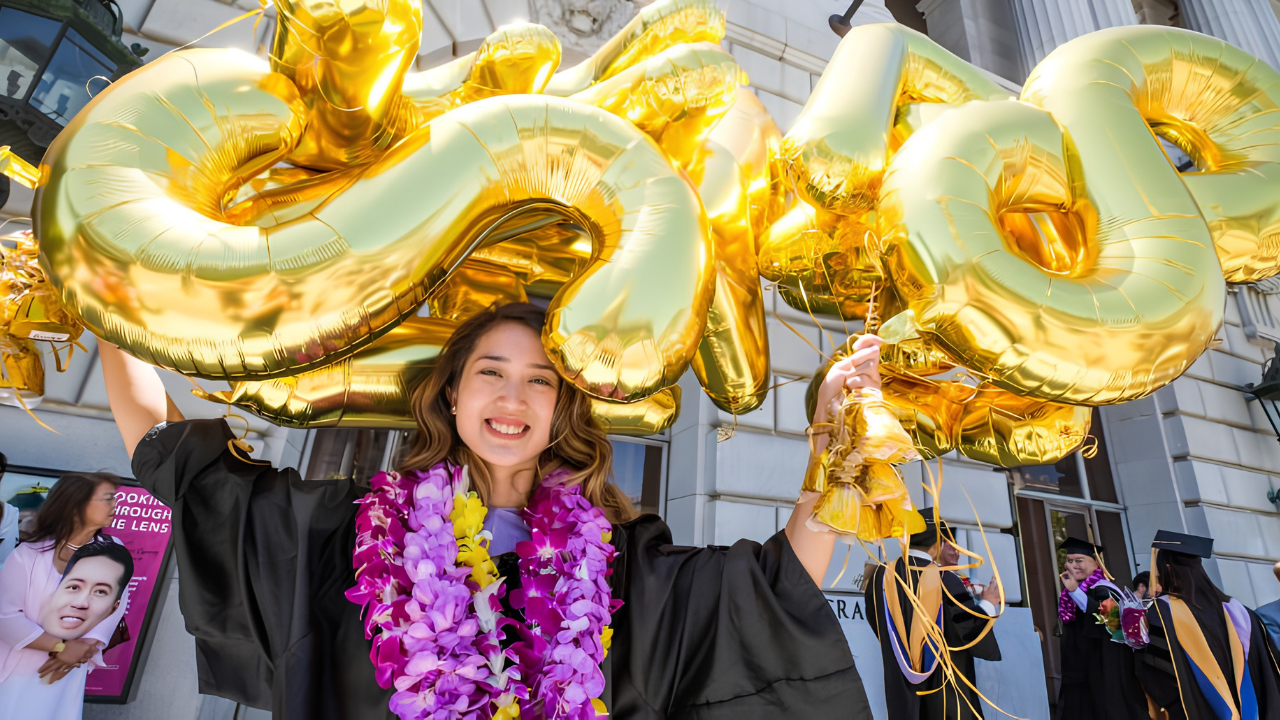 A graduate dons festive leis and balloons after the School of Dentistry commencement ceremony.
