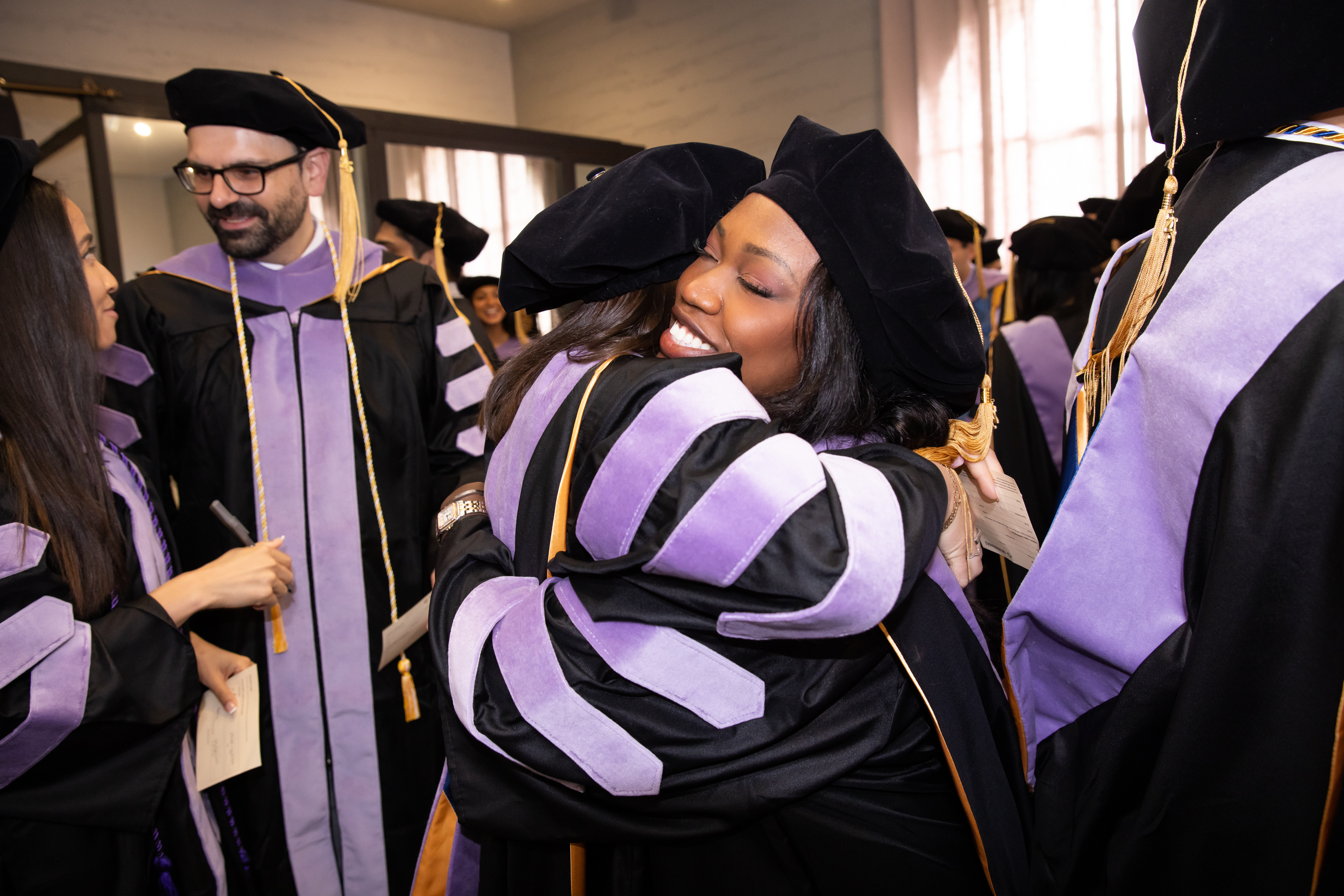 Dentistry graduates hug at 2025 commencement ceremony