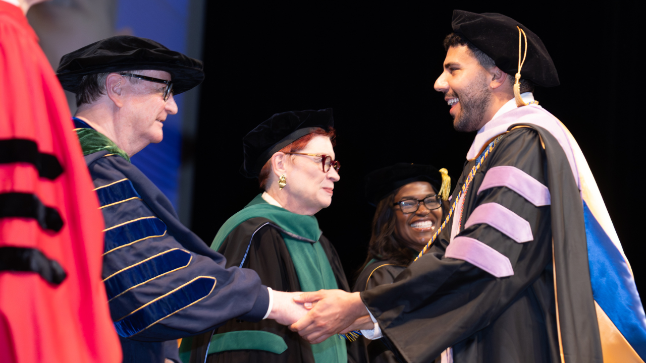 Chancellor Hawgood, Catherine Lucey, and Renee Navarro congratulate a graduate