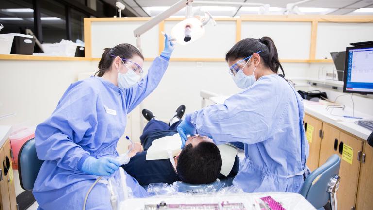 First-year dental student Tanya Varimezova, left, and Yuvika Raj Kumar, a third-year student in the international dental program, perform a dental procedure on Jeffrey Martinez. Photos by Susan Merrell/UCSF