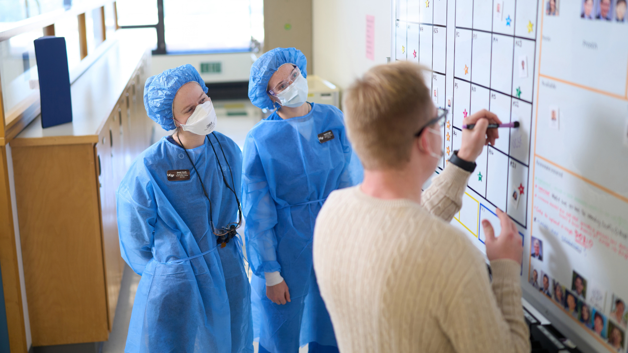 Dental students with clinic administrator at the scheduling board.