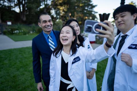 students take selfies with dean reddy at white coat ceremony 2024