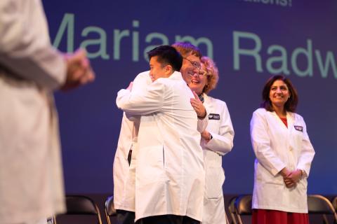 student shakes hand of faculty after being coated