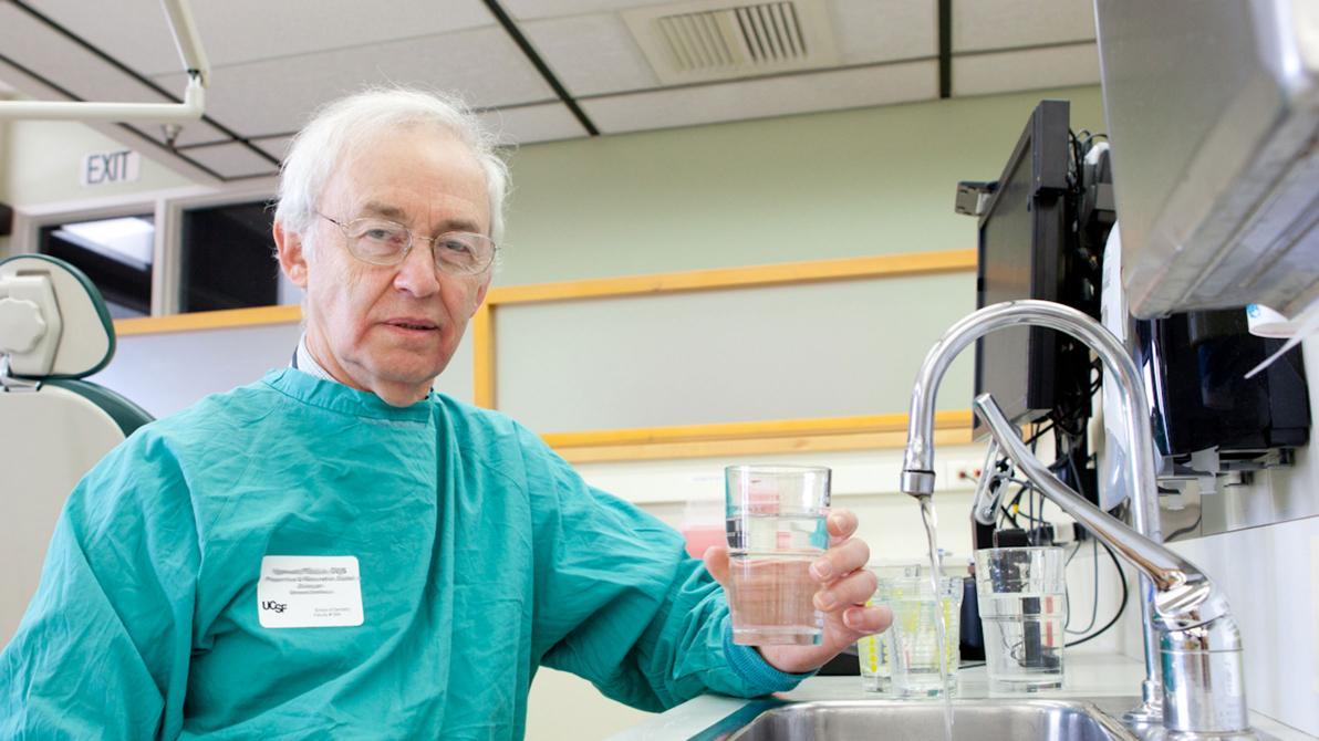 faculty dentist holds beaker of water