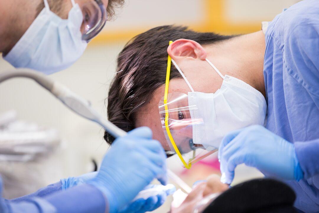 First-year dental student Steven Bonzell, left, and Paul Kim, DDS, a post graduate in the Oral and Maxillofacial Surgery program, perform a dental procedure on Isaiah Wallawingbull, in the Community Dental Clinic held every Wednesday evening.